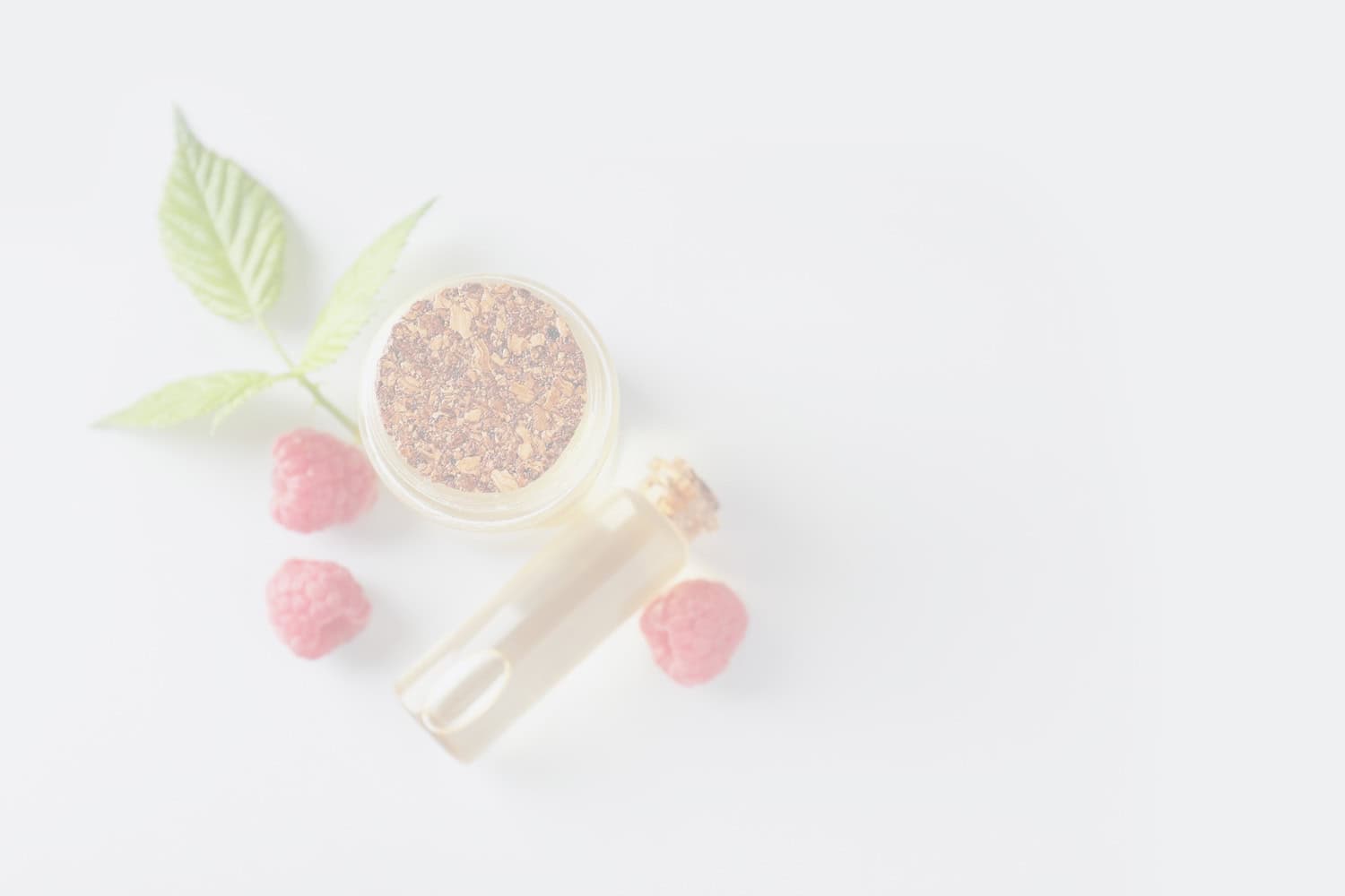 Rich raspberry oil and plant extracts in a glass dropper bottle with fresh raspberries and green leaves, promoting natural skincare and beauty products.
