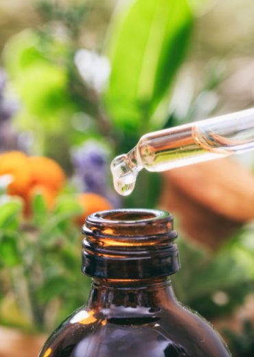 High-quality CBD oil being extracted using a glass dropper and dark glass bottle in an outdoor farm setting, emphasizing natural hemp product extraction.